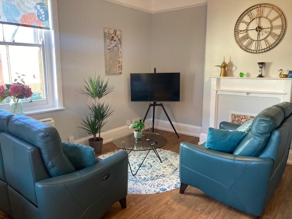 a living room with two blue chairs and a tv at Stylish Flat in Yeovil Somerset in Yeovil