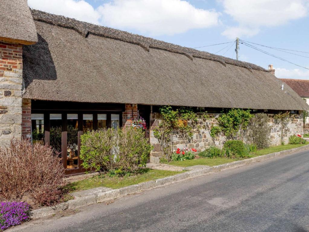 a stone building with a thatched roof on a street at 3 Bed in Coombe Keynes DC029 in Wool