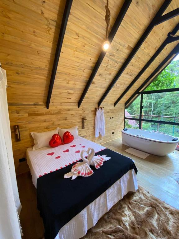 een slaapkamer met een bed en een bad in een kamer bij chalé Platanus in Campos do Jordão
