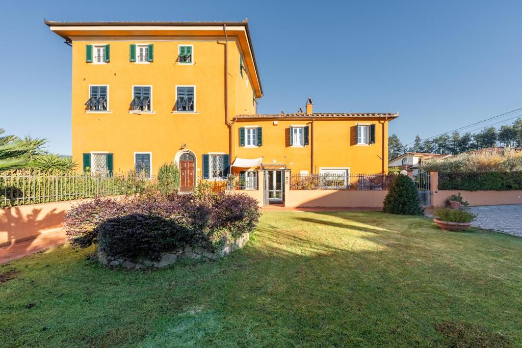 a large yellow house with a yard in front of it at Villa Petri in Uzzano