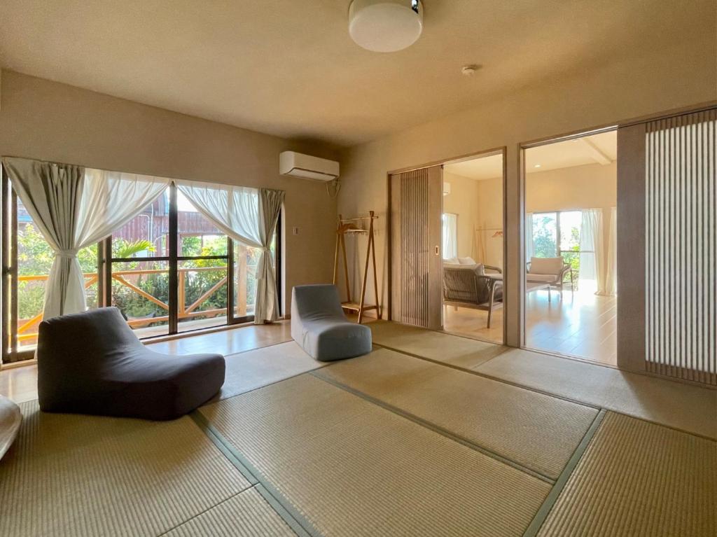 a living room with two chairs and a living room with windows at Yoronto - Vacation STAY 18850v in Yoron