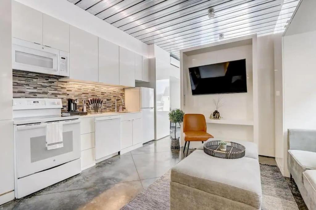 a kitchen with white cabinets and a couch and a tv at KCM Mikros Smart Apartments 7 in Cleveland