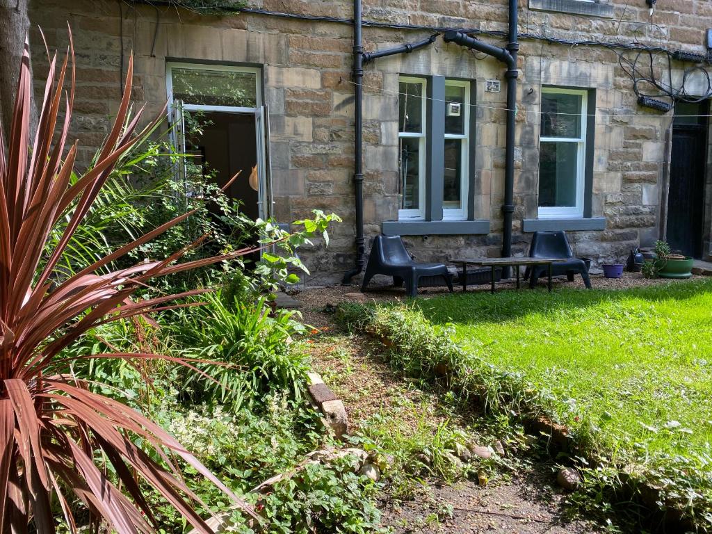 a stone house with a bench in the yard at Garden Flat in Edinburgh
