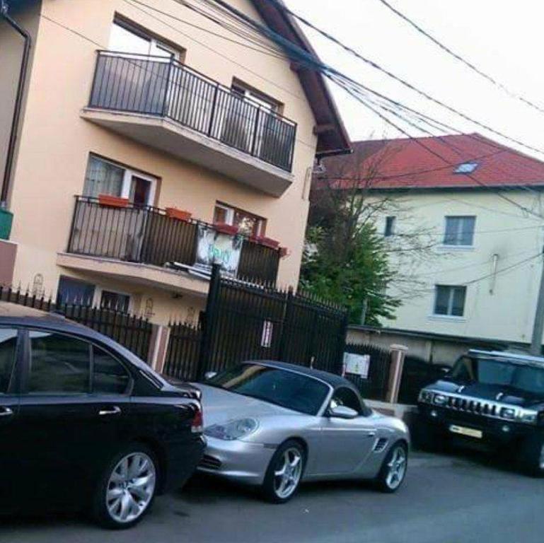 dos autos estacionados en un estacionamiento frente a un edificio en Casa Thomas Cluj en Cluj-Napoca