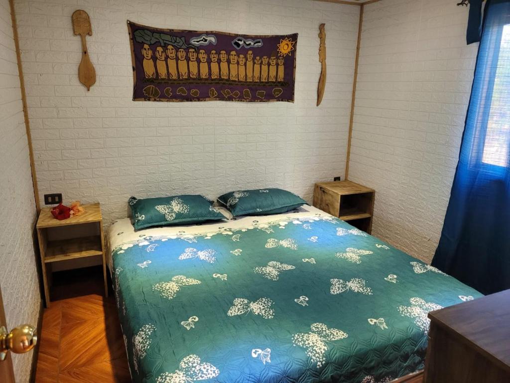 1 dormitorio con 1 cama con edredón y almohadas azules en Cabaña tongarikii, en Hanga Roa