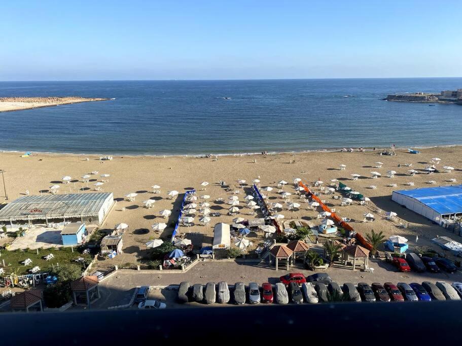 una playa con muchos coches y sombrillas en 3-Bedroom Apartment with Stunning Sea-Side View en Alexandria