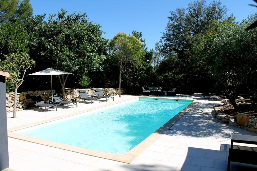 einen Pool mit Stühlen und einem Sonnenschirm in der Unterkunft LES GITES DE VALERIE Appartement de 50m2 avec parking privé in Nîmes