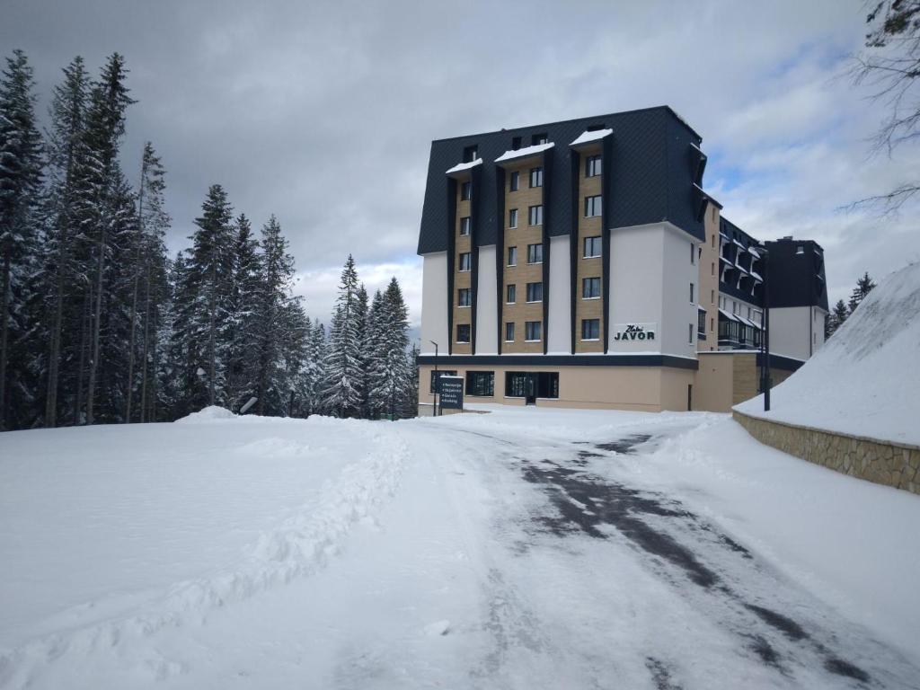um grande edifício na neve com uma estrada nevada em Apart Hotel Zlatni Javor, Apartment 410 em Jahorina
