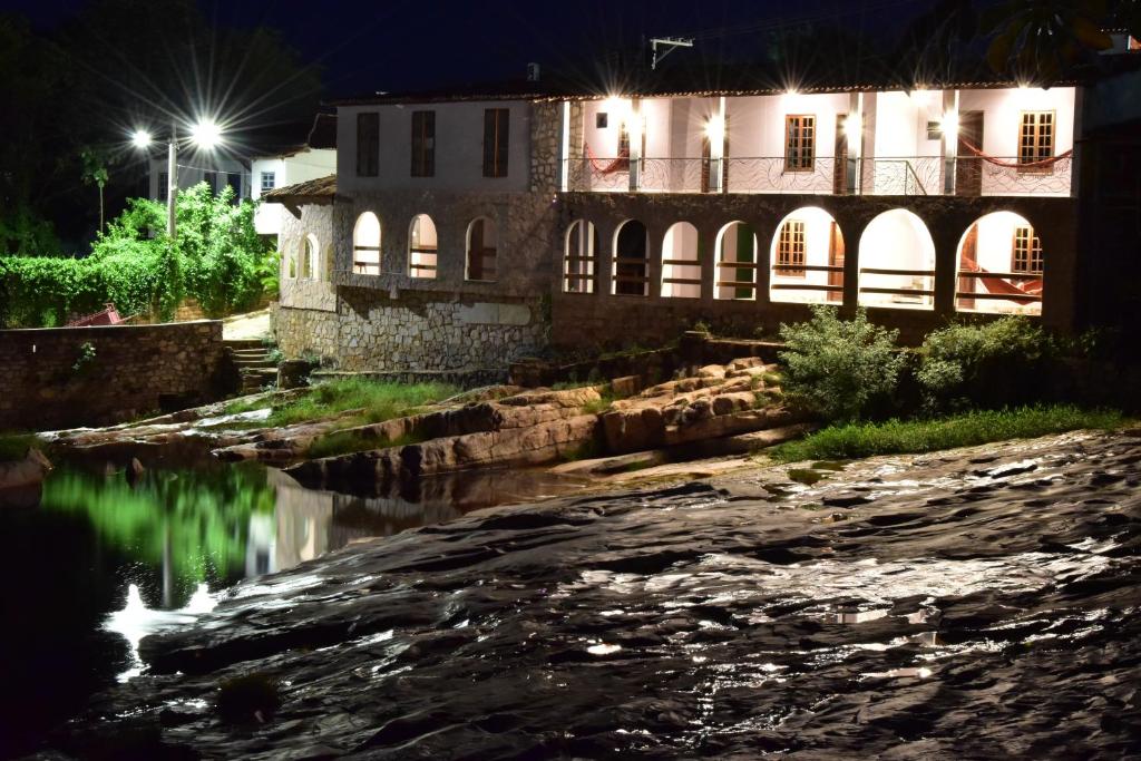 a building next to a river at night at Serra Grisante Pousada Bed and Breakfast in Lençóis
