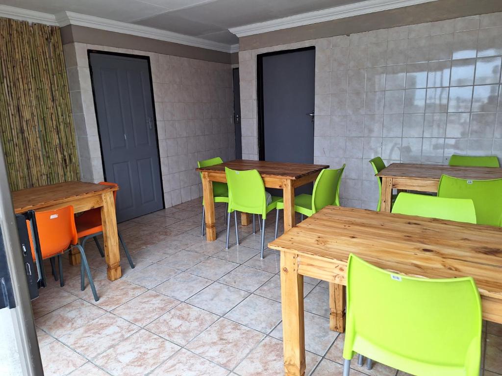 Habitación con mesas de madera y sillas verdes. en Tsakane View Guesthouse en Brakpan
