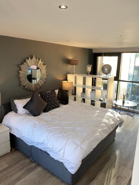 a bedroom with a large bed with a mirror on the wall at Deluxe City Centre Studio Apartment with Balcony & City Views - FREE WIFI NETFLIX, GYM ACCESS - WESTONE in Sheffield