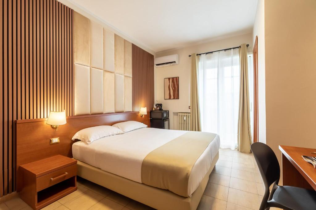 ローマにあるAlbaDomus Affittacamereの大きなベッドとデスクが備わるホテルルームです。