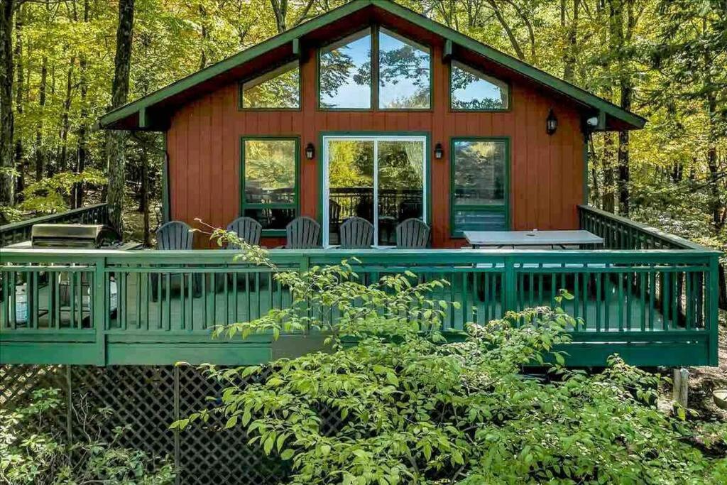 una cabaña en el bosque con una terraza verde en *Bear Hugs Chalet* SKI*Games *NewHotTub*Fire Pit, en Lake Harmony