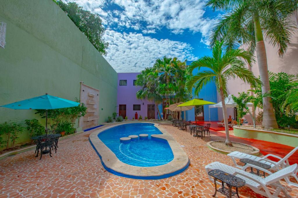 a pool with chairs and umbrellas next to a building at Hotel del Gobernador in Mérida