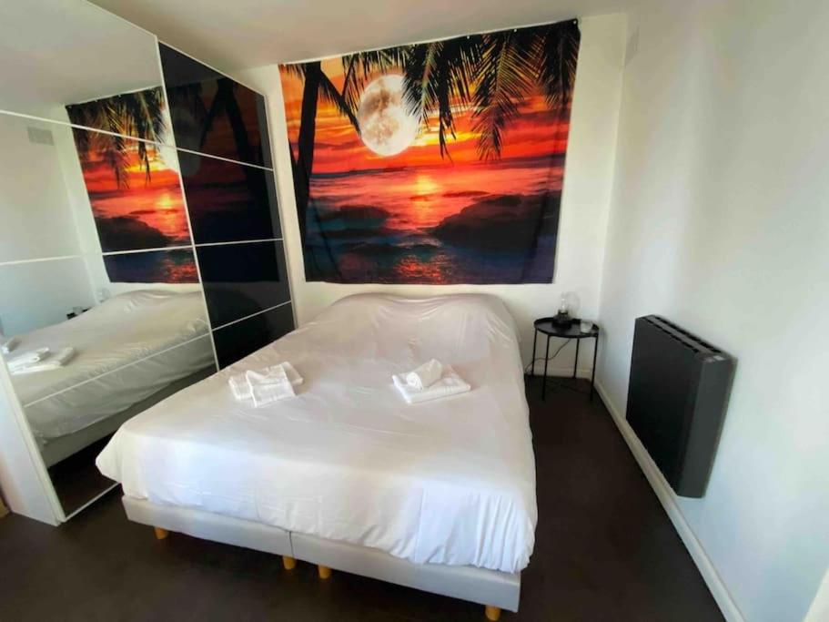 um quarto com uma cama branca e um quadro na parede em Appartement 41m2 wifi, climatisé : La Grande Motte em La Grande-Motte