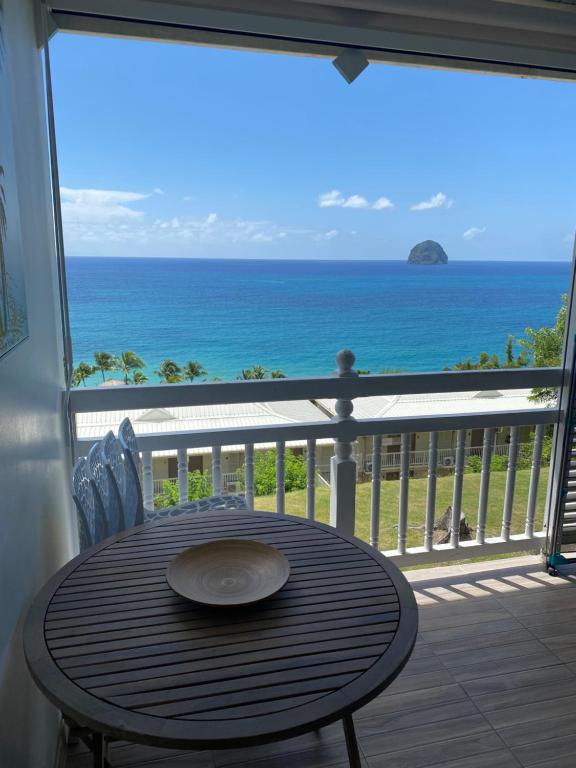 a table on a balcony with a view of the ocean at MY Studio vue mer in Le Diamant