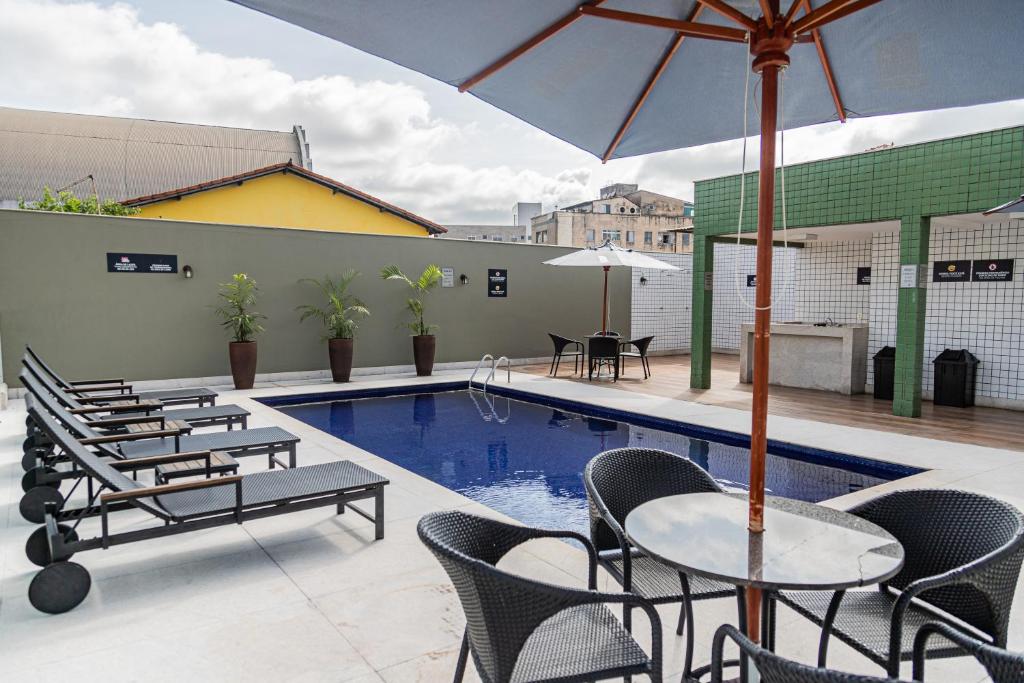 a patio with tables and chairs and a swimming pool at Hotel Eldorado Flat in Contagem