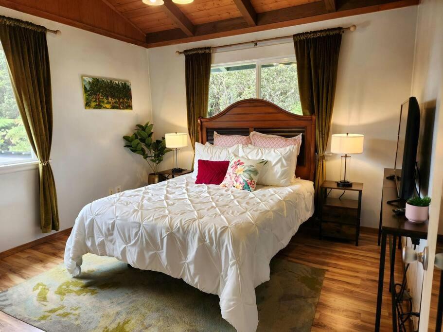 a bedroom with a large white bed with pillows at Lava Lover's Getaway in Volcano