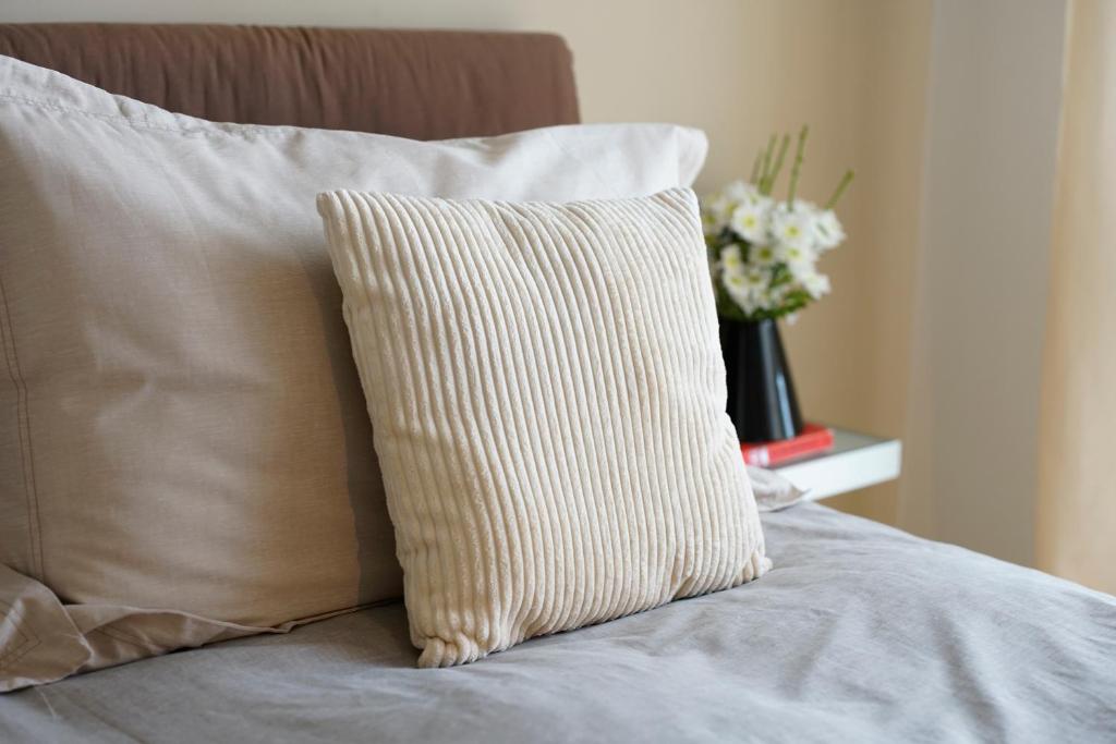 a pillow sitting on a bed with a vase of flowers at Venere B&B in Catania