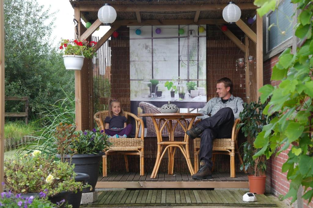 a man and a woman sitting at a table on a patio at B&B Dirosa in Onderdijk