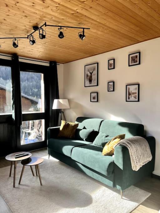 sala de estar con sofá verde y ventana en Appartement neuf à 400 m des remontées avec Sauna, en La Chapelle-dʼAbondance