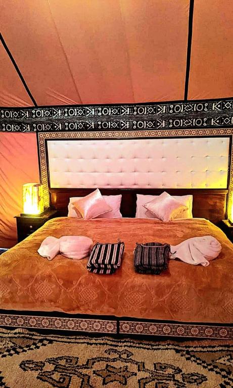 a bedroom with a large bed with two towels on it at Luxury Desert Camp in Merzouga