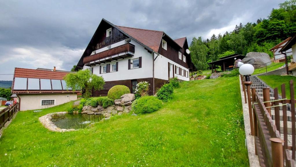 a house on a grassy hill with a creek at Ubytování Na Výsluní Tanvald in Tanvald