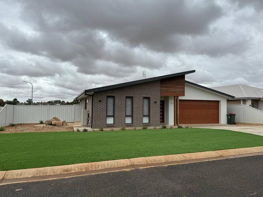 une maison avec une pelouse verte devant elle dans l'établissement Modern luxury - Brand new home, à Parkes