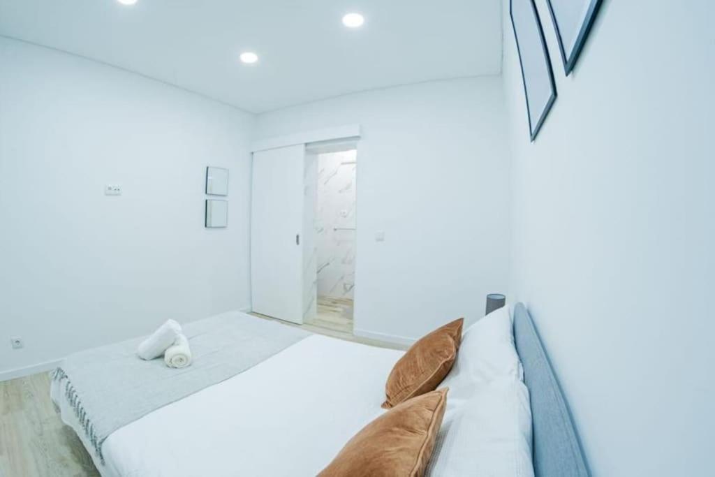 a white bedroom with a bed with pillows at Bright and modern flat with air-con and free parking in Moita