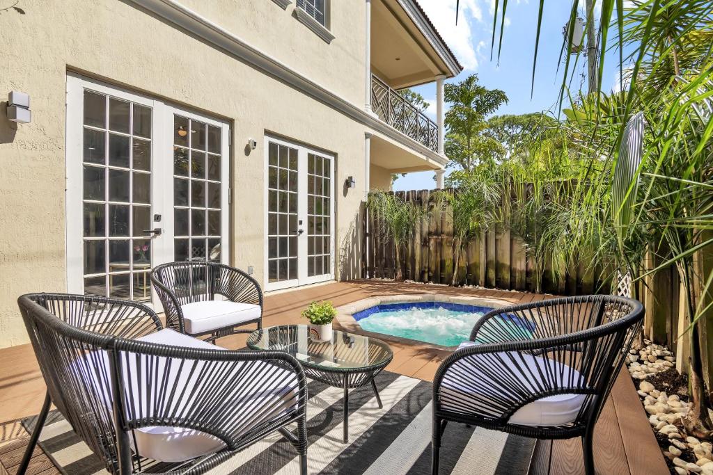 un patio con sillas, una mesa y una piscina en Light Filled Home Walk to Wilton Dr - Hot Tub!, en Fort Lauderdale