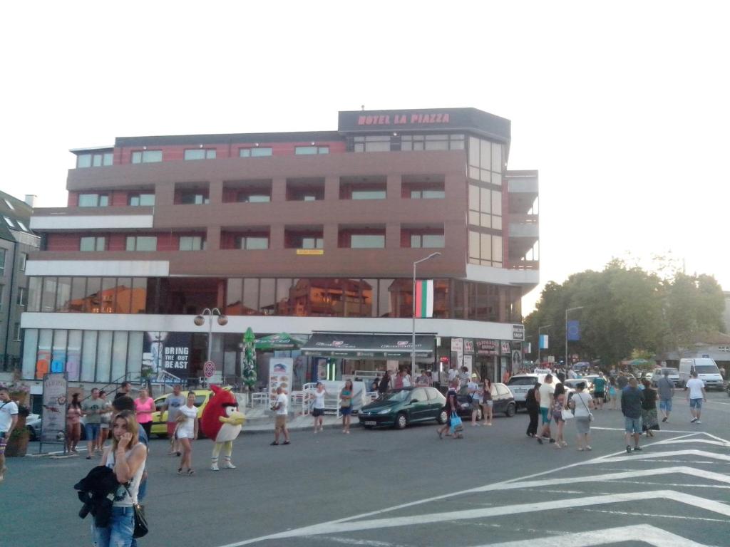 una multitud de personas cruzando una calle frente a un edificio en La Piazza Primorsko Rooms & Apartments, en Primorsko