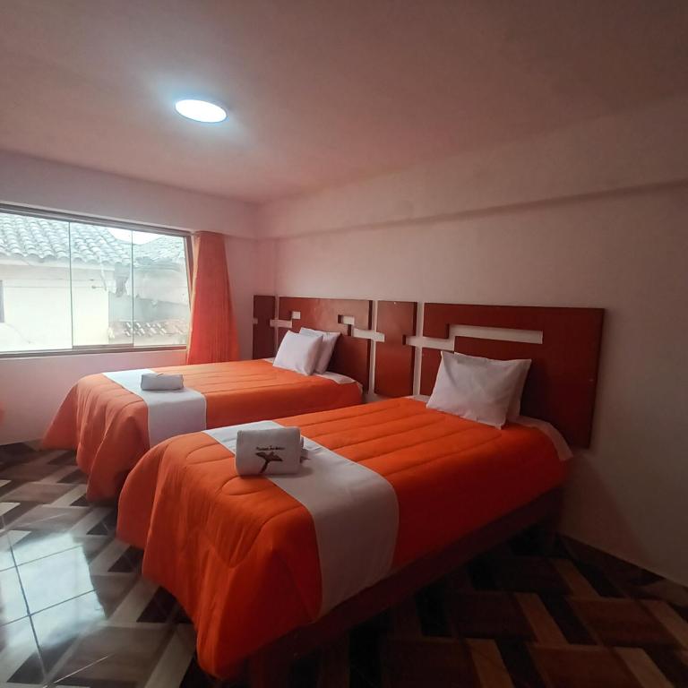 two beds in a room with orange and white at VILLA MARAS Hotel in Maras
