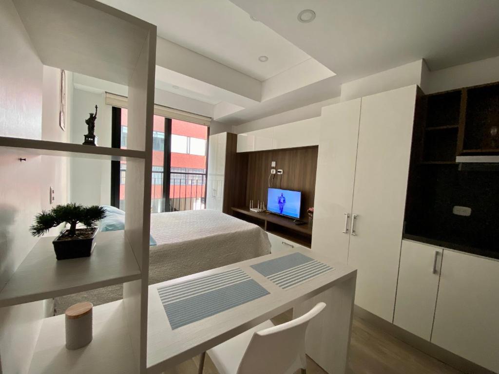 a bedroom with a bed and a desk and a television at Apartamento grande Soho 39 in Bogotá