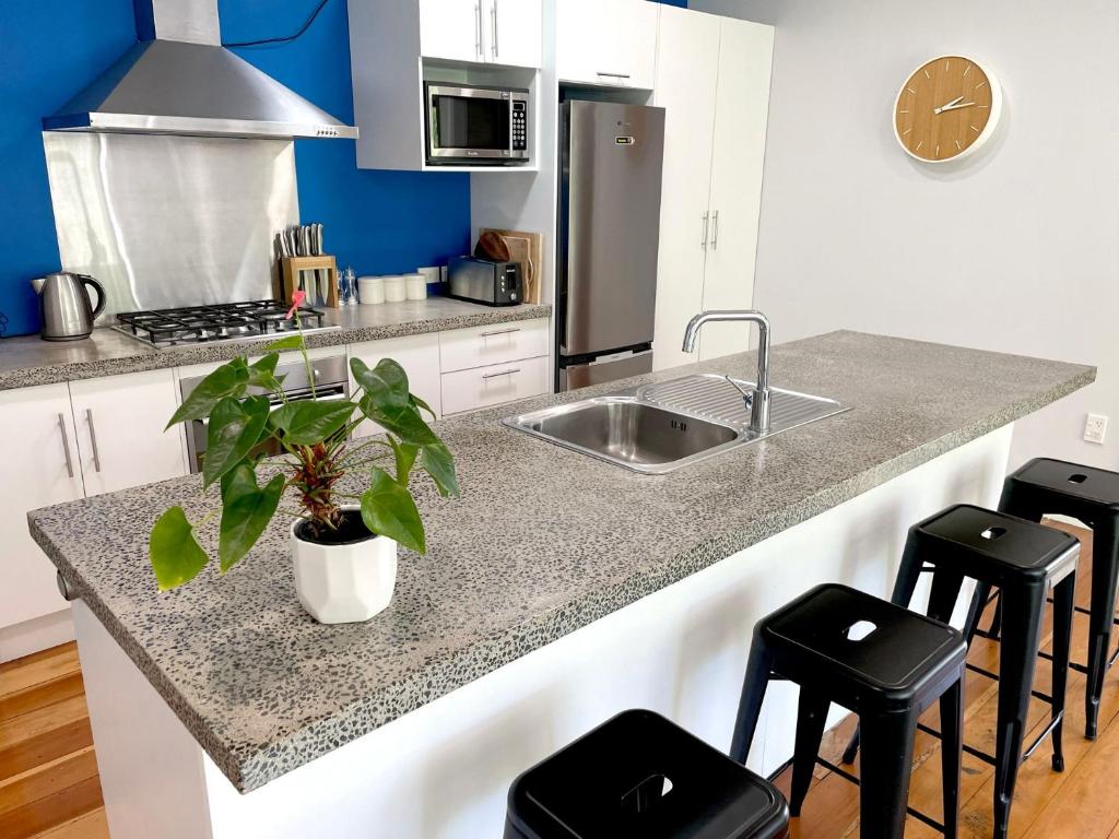 a kitchen with a sink and a counter with stools at Huatoki Hideaway Peaceful Central Location in New Plymouth
