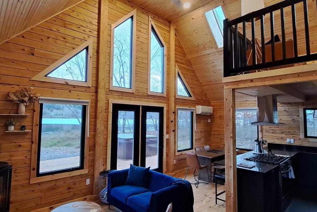 eine Hütte mit Fenstern und einem blauen Sofa in einem Zimmer in der Unterkunft Islander Lodge - Lochaber Lake Lodges in Antigonish