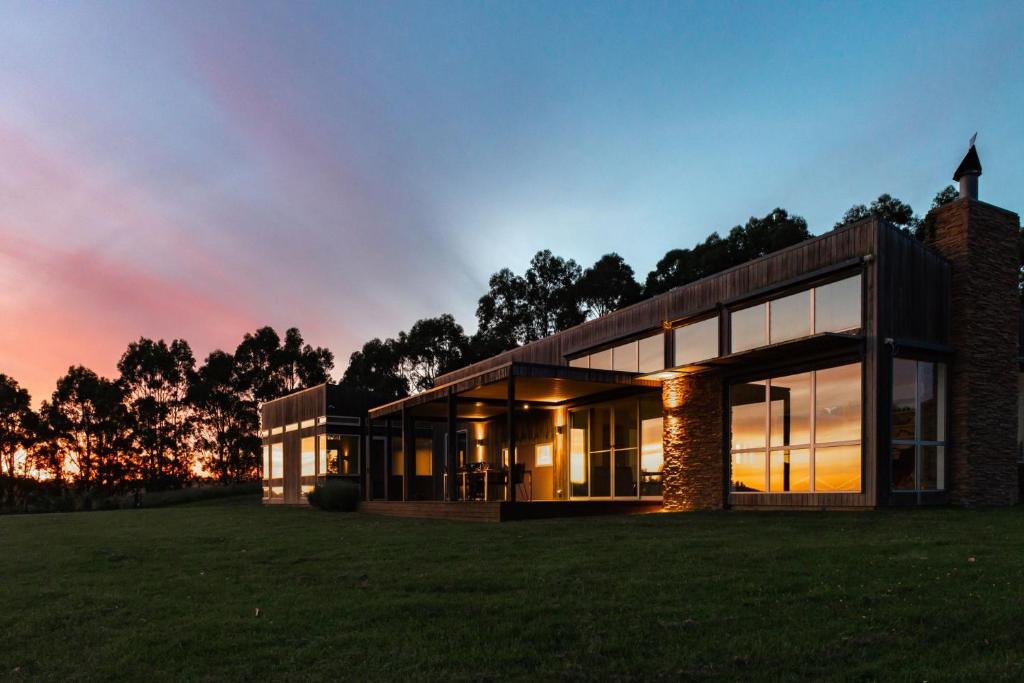 uma casa num campo com um pôr-do-sol em Tall Trees Country Escape em Foster