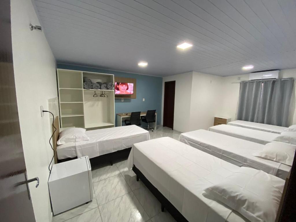 um quarto de hospital com três camas e uma mesa em Pousada Route 58 em Gravataí
