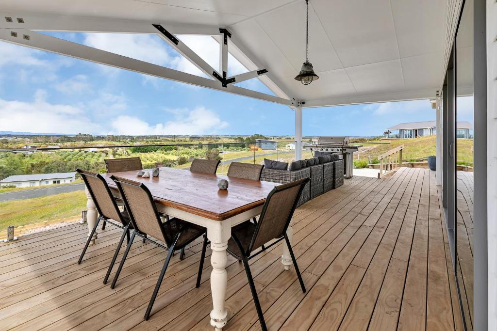 a wooden table and chairs on a wooden deck at Seaglass - Karikari Peninsula Holiday Home in Kaitaia