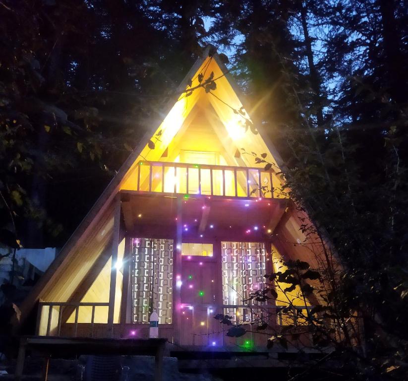 uma casa na árvore com luzes à noite em Pinehill cottage em Jibhi