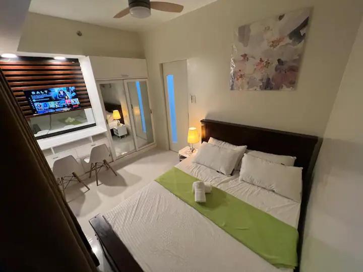 a bedroom with a bed and a desk and a television at Brenthill Baguio condo unit near SM baguio in Baguio