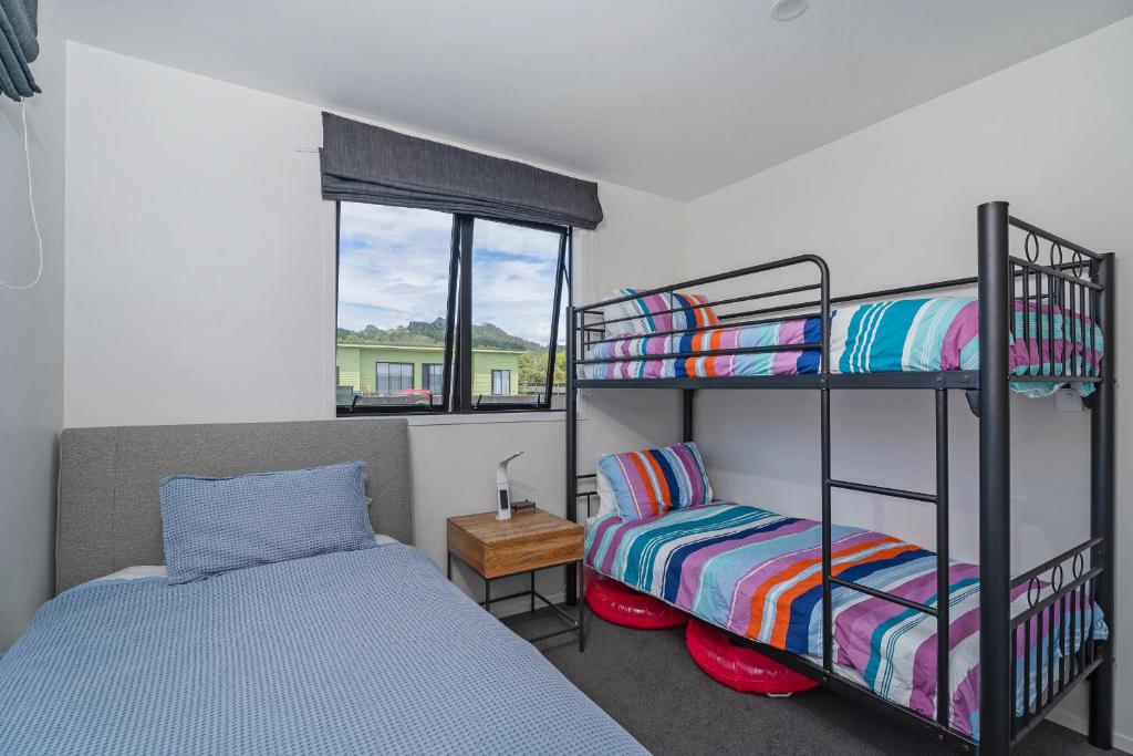 a bedroom with two bunk beds and a bed at Hosts on the Coast - Leighs' Luxury Retreat in Cooks Beach