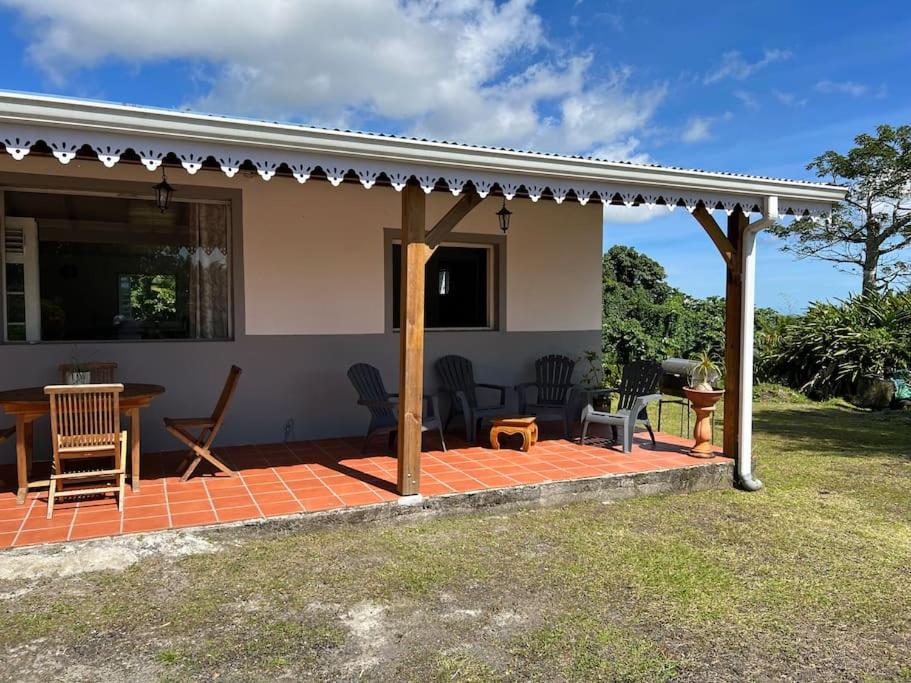 ein Haus mit einer Terrasse mit einem Tisch und Stühlen in der Unterkunft 972B-Coin de verdure au pied de la Montagne Pelée in Le Morne Rouge