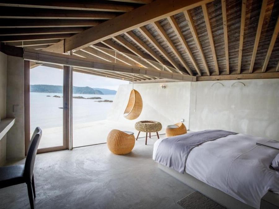 a bedroom with a bed and a view of the ocean at Denpaku The Beachfront MIJORA in Amami