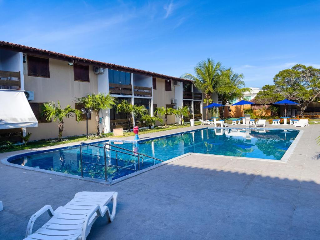 una piscina con sillas y un hotel en Condomínio Portal do Atlântico, en Porto Seguro