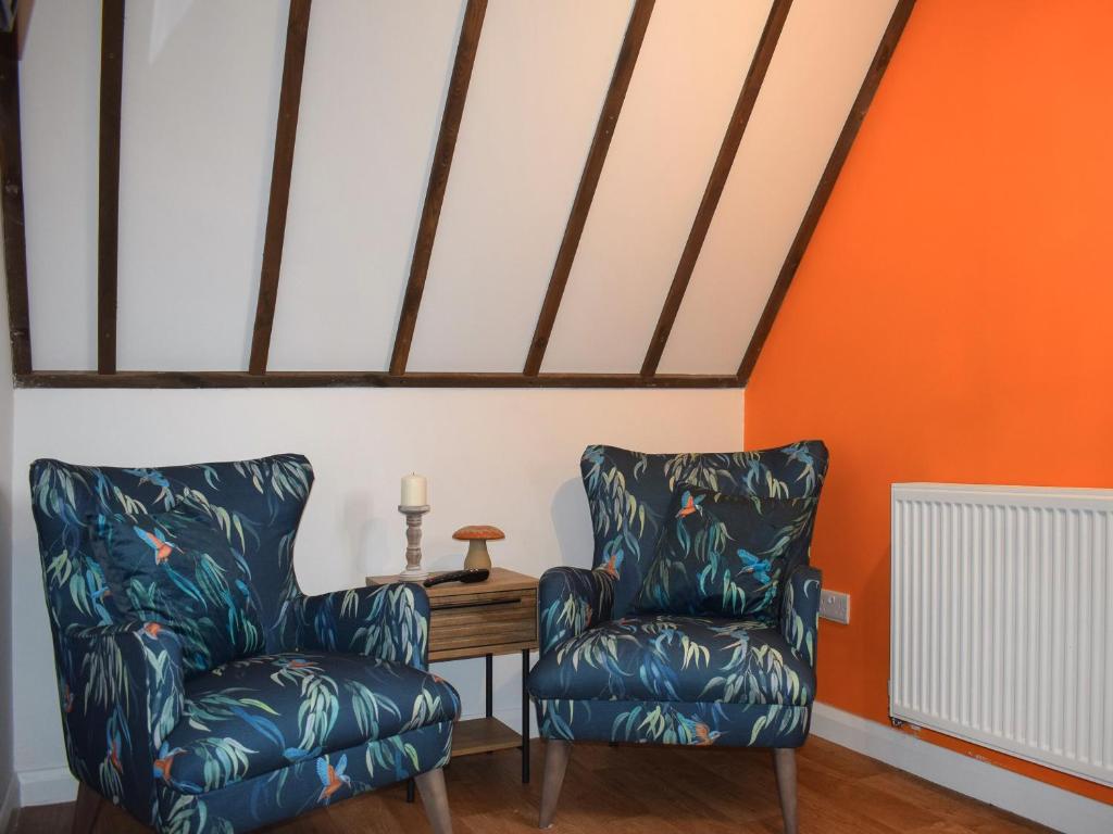 twee stoelen en een tafel in een kamer met oranje muren bij Kingfisher Granary in Ashburnham