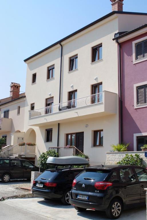 dos autos estacionados en un estacionamiento frente a un edificio en Guesthouse Residence Major, en Rovinj