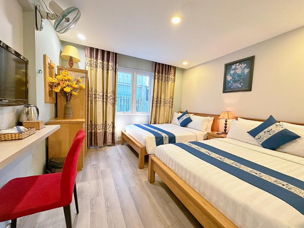 a hotel room with two beds and a red chair at LUAN VU Hotel - Bui Vien Walking Street in Ho Chi Minh City