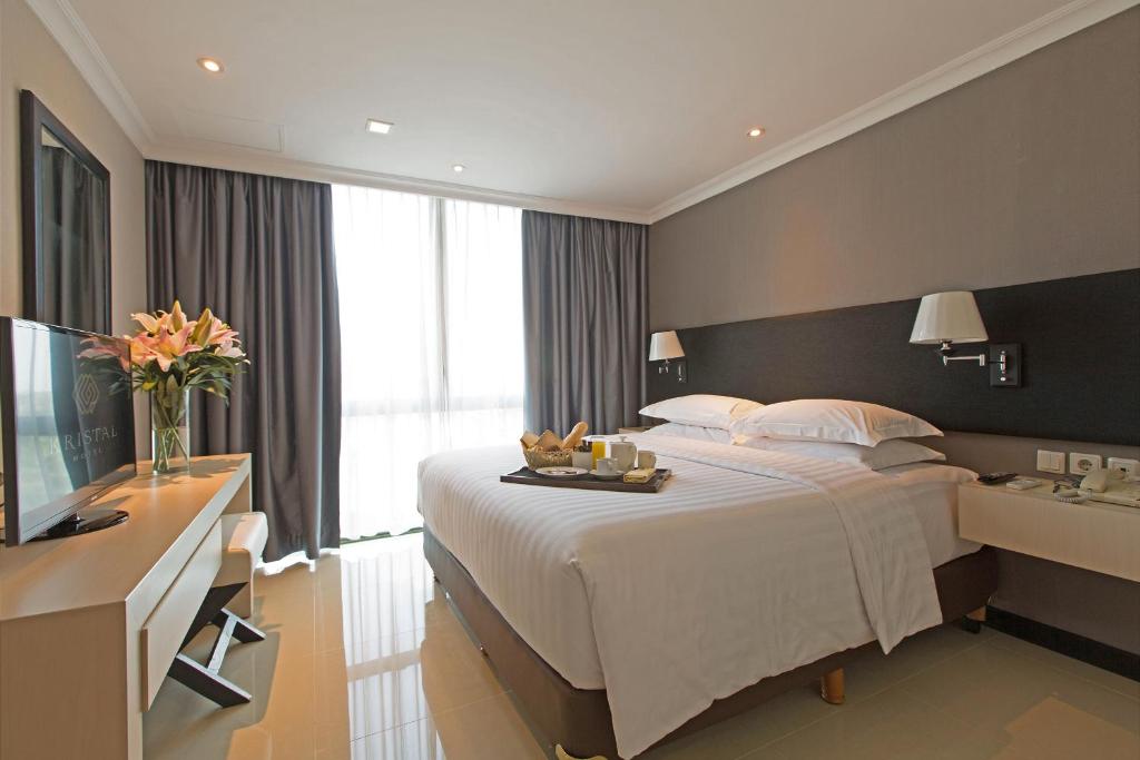 una camera d'albergo con un grande letto e una TV di Kristal Hotel Jakarta a Giacarta