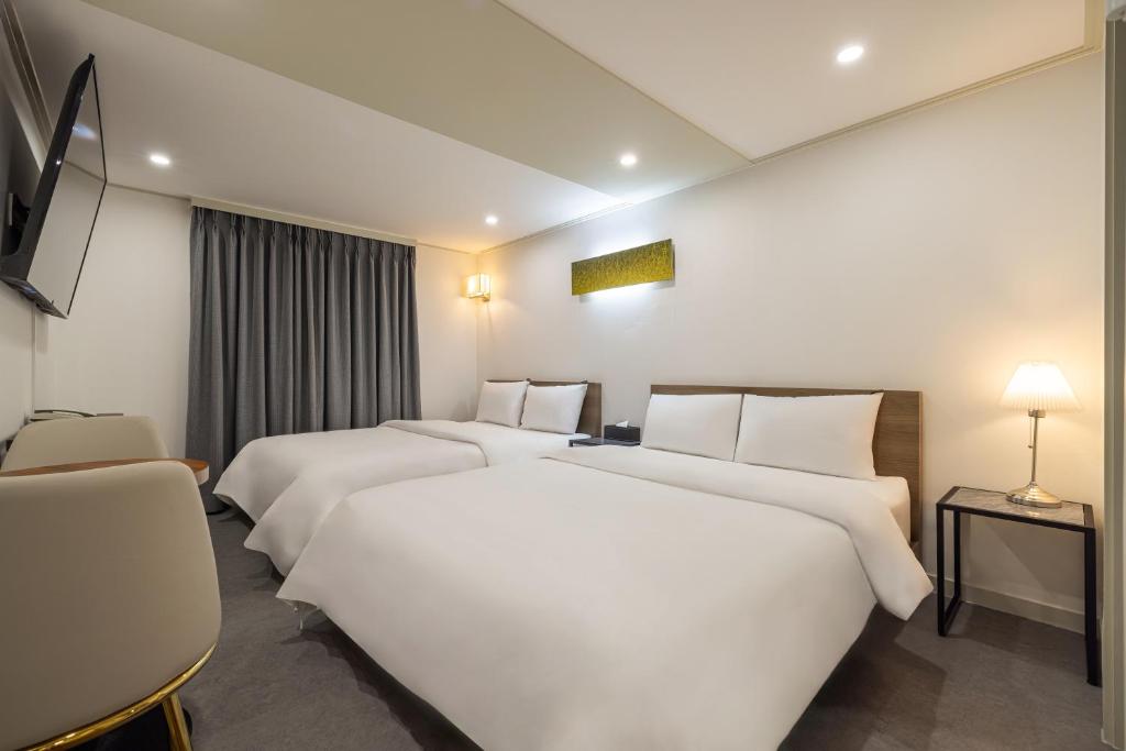 um quarto de hotel com três camas e uma televisão em Hotel Stay Inn em Seul