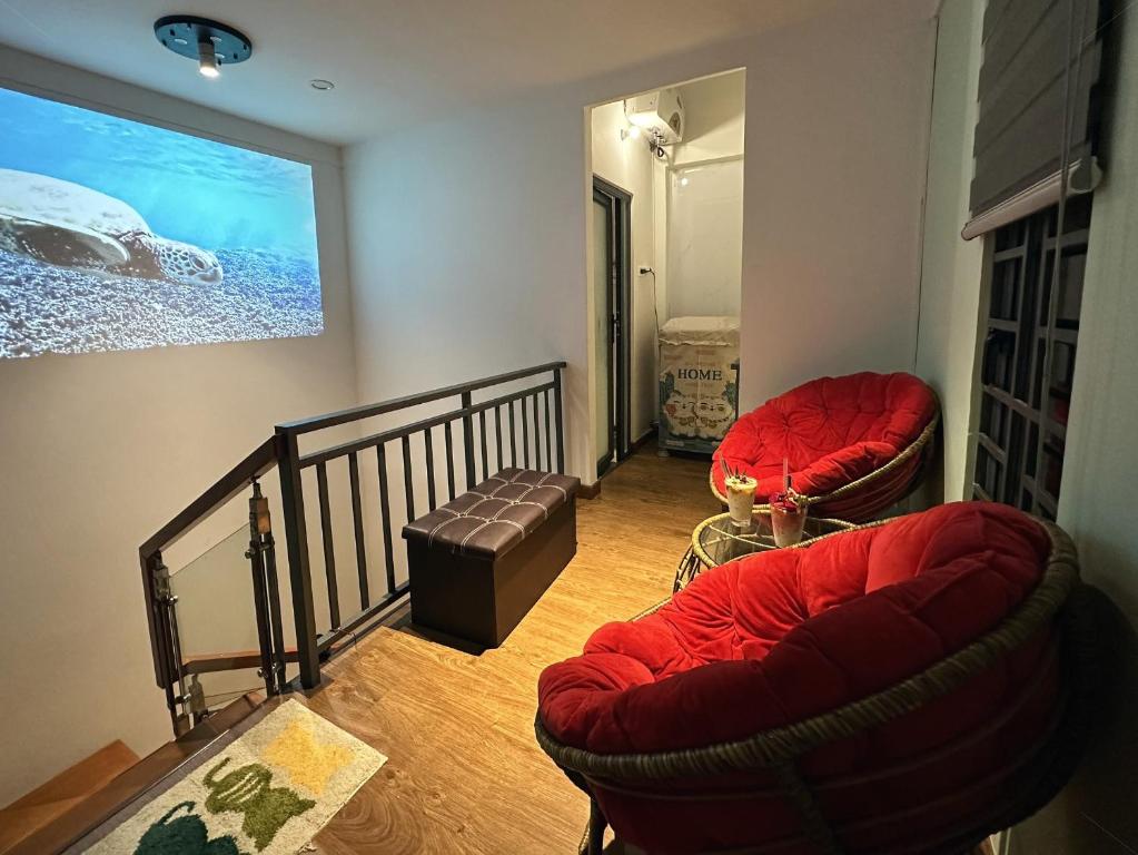 a living room with two red chairs and a staircase at Gachilly House - Your Cozy Home In The Heart Of The BMT City in Buon Ma Thuot